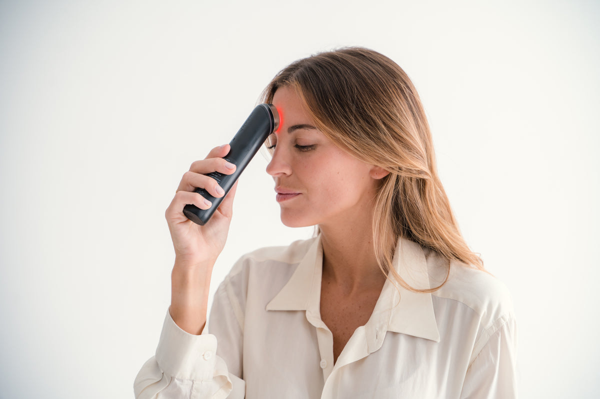 Mujer aplicando el Medicube AGE-R Booster Pro en la frente, demostrando el funcionamiento del dispositivo en la zona superior del rostro.