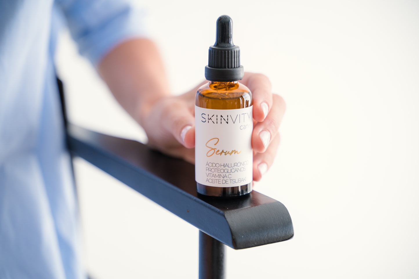 Sérum facial SKINVITY apoyado sobre una mano, mostrando el envase dorado y su textura ligera.