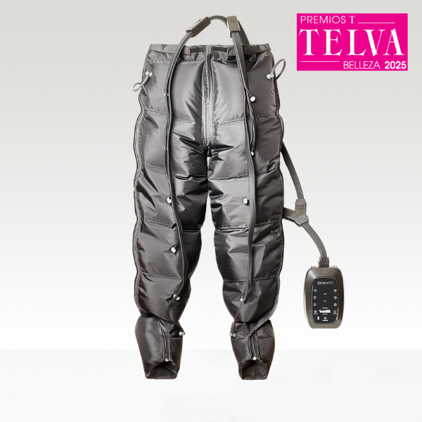 Pantalones de presoterapia PressTech colgados junto al compresor digital SKINVITY, mostrando su diseño completo, cámaras de aire y conectores, con sello TELVA Belleza 2025.