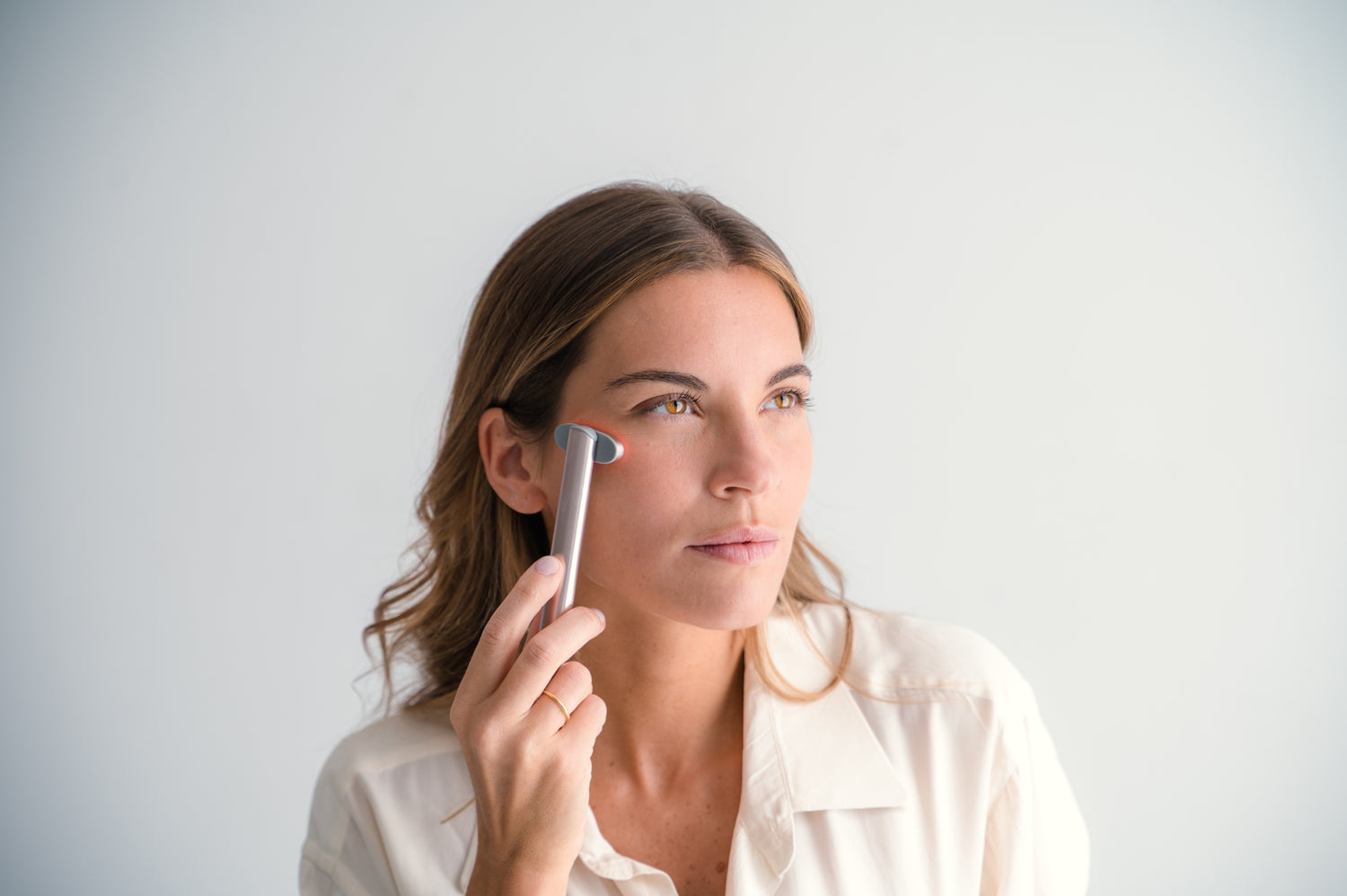 Mujer utilizando el dispositivo FixEye+ en la zona del contorno de ojos para un tratamiento de rejuvenecimiento y drenaje.