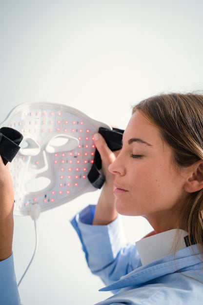 SKINVITY SILICONE LED MASK SE VEN LOS FOCOS DE LUZ LED ROJA INTERIORES Y LA FORMA DE LA MÁSCAR,A MISMA QUE ES SOSTENIDA POR UNA MUJER
