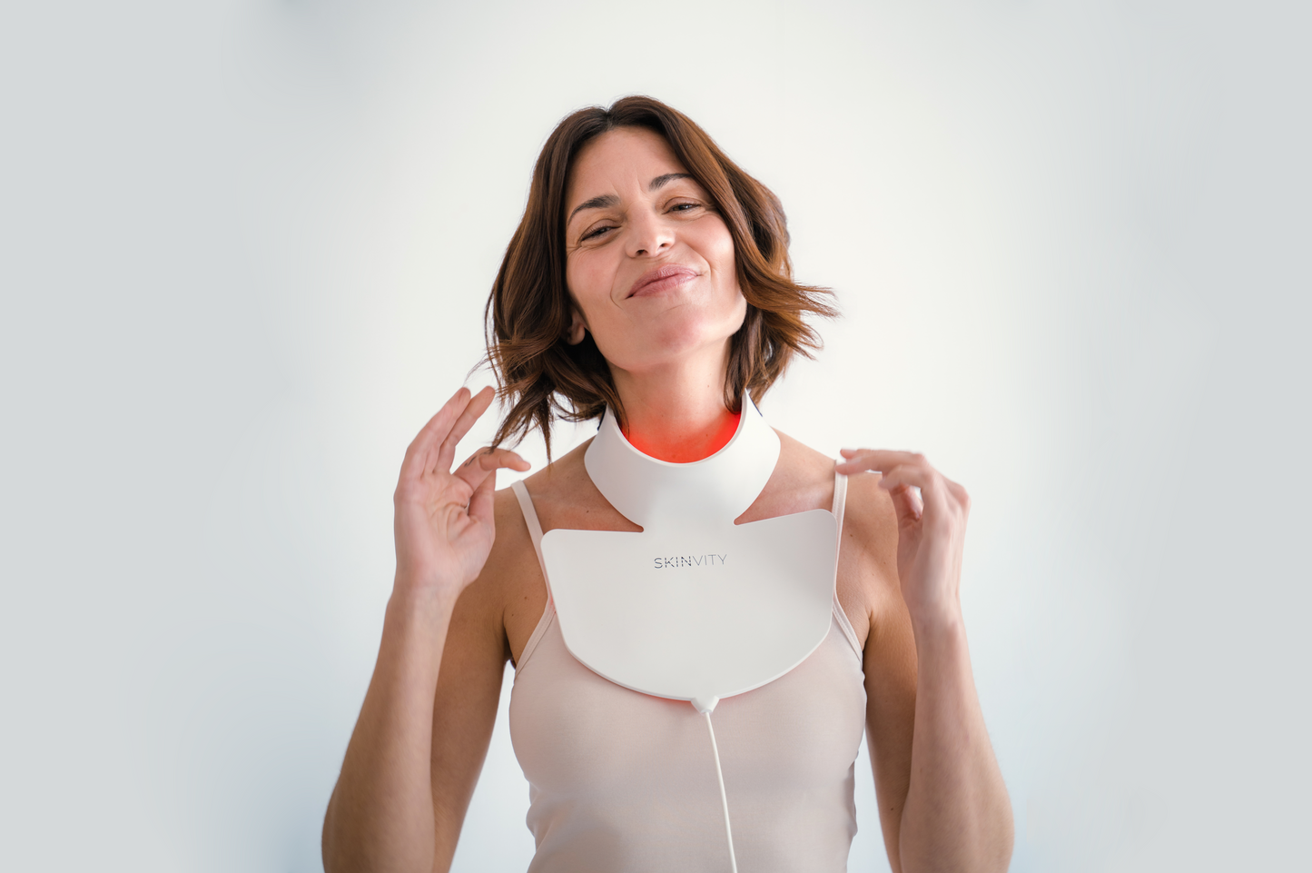 Mujer utilizando el dispositivo Silicone LED Neck con luz LED roja para el cuidado de la piel del cuello y escote.