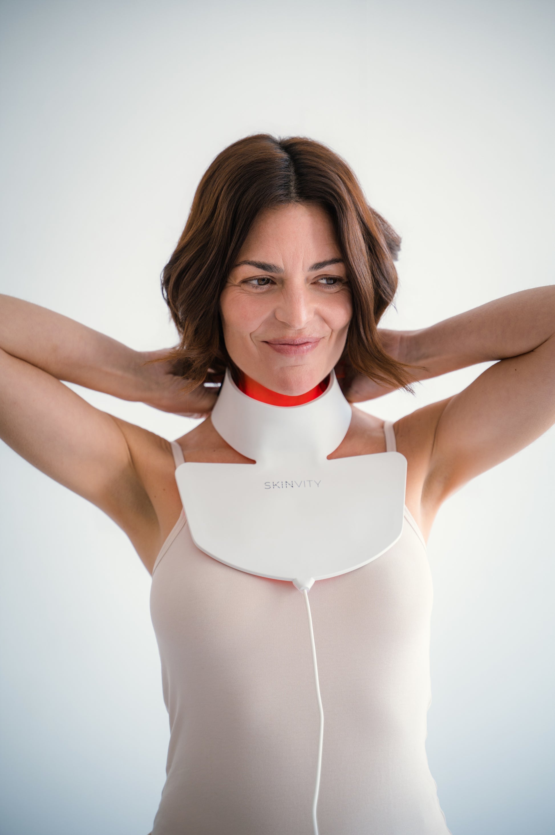 Mujer usando Silicone LED Neck con terapia de luz LED roja para rejuvenecer y cuidar la piel del cuello y escote.