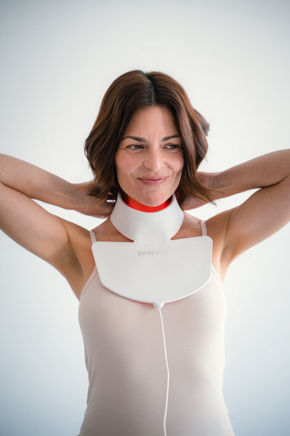 Mujer usando Silicone LED Neck con terapia de luz LED roja para rejuvenecer y cuidar la piel del cuello y escote.