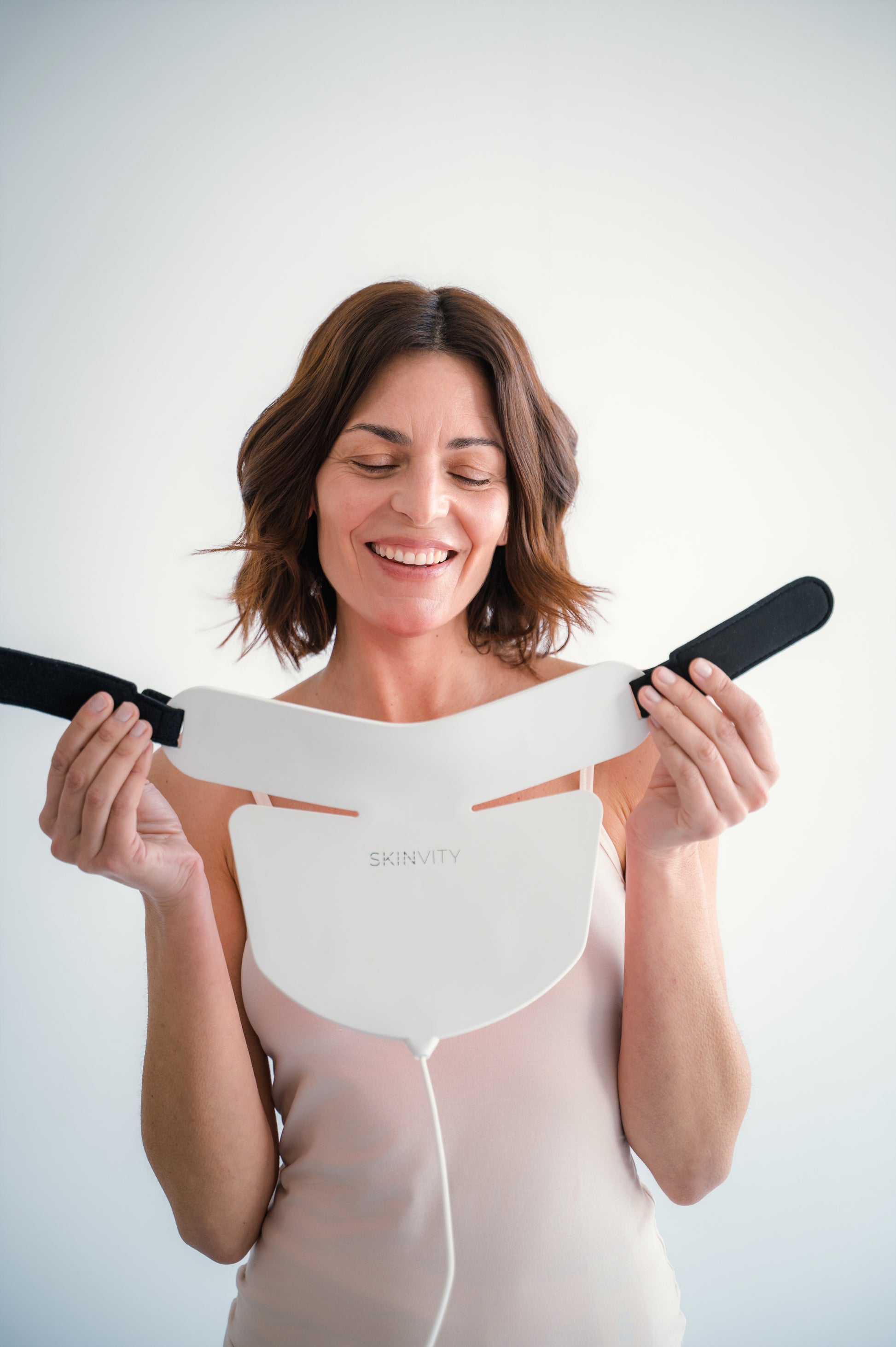 Mujer mostrando el dispositivo Silicone LED Neck de silicona flexible con cierre ajustable para tratamiento LED en cuello y escote.