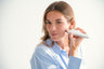 Mujer aplicando el dispositivo facial Envig Edge en la mejilla para tratar arrugas, manchas e imperfecciones mediante radiofrecuencia fraccionada.